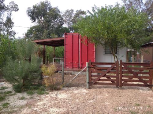 czerwony dom z bramą i płotem w obiekcie Tu lugar de relax! Se reserva solo con seña w mieście Guazuvirá