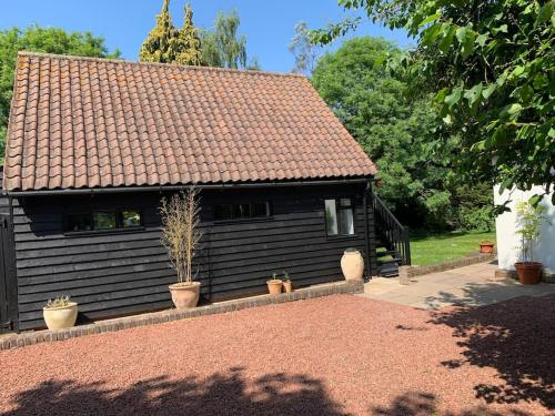 a black house with potted plants in front of it at Newly converted 2 storey, 2 bedroom, barn in Long Melford in Long Melford