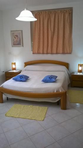 a bedroom with a bed with two blue pillows on it at Sa Domu Sarda casa vacanza in Piscinas