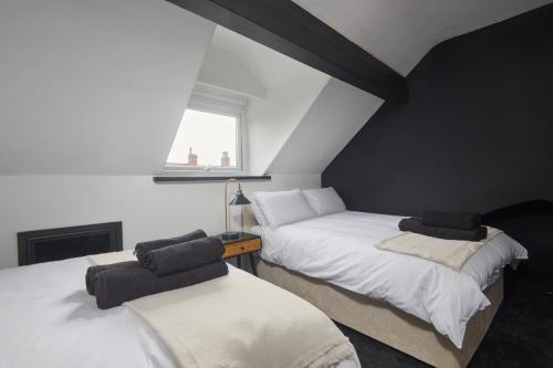 two beds in a attic room with a window at Victoria House in Leeds