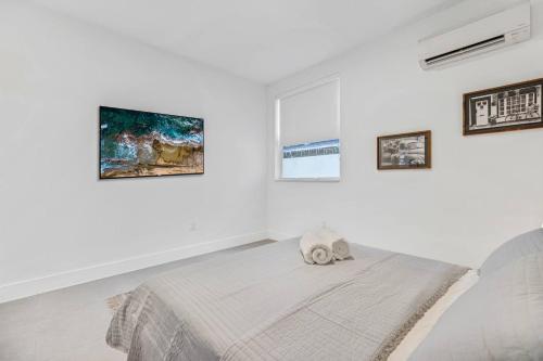 a white bedroom with a bed with a stuffed animal on it at Up to 16 guests! Modern house near Wynwood in Miami