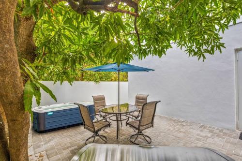 a table and chairs with an umbrella and a hot tub at Up to 16 guests! Modern house near Wynwood in Miami