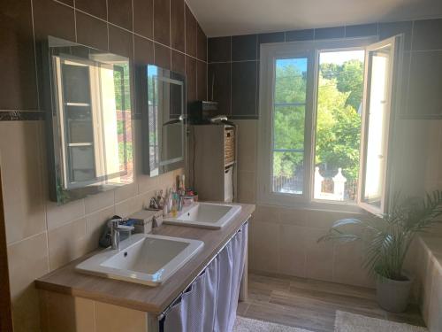 ein Badezimmer mit zwei Waschbecken und zwei Fenstern in der Unterkunft Les 5 timbres in Montpellier-de-Médillan