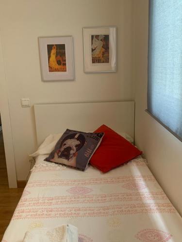 Una cama con una almohada roja encima. en Apartamento en el Centro, en Sevilla