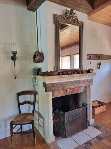- une cheminée avec un miroir et une chaise dans la chambre dans l'établissement La Borie Blanche en Périgord Noir, à La Borie Blanche