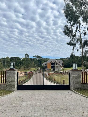 a gate to a driveway with a house in the background at WoodStone Hotel Fazenda in Gramado
