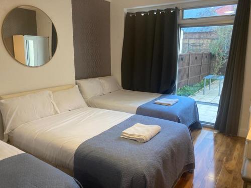 Zimmer mit 2 Betten, einem Spiegel und einem Fenster in der Unterkunft TWIN TOWERD HOTEL in London