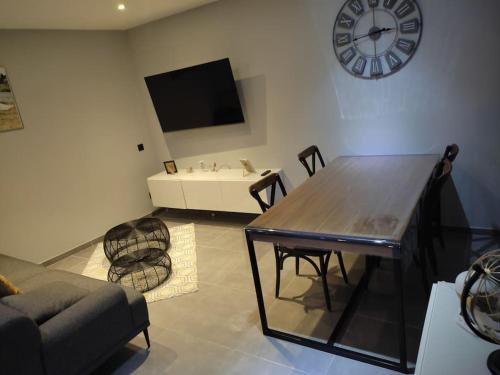 ein Wohnzimmer mit einem Tisch und einer Uhr an der Wand in der Unterkunft Villa 110m2, 3 chambres, piscine. in Uchaud
