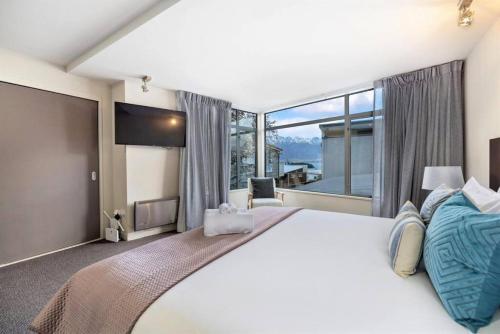 a bedroom with a large bed and a large window at Manaaki Alpine Retreat Central CBD - SPA - Garage in Queenstown