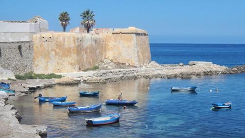 a group of boats in the water near a castle at Casa Granata in Trapani