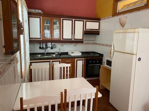 La cuisine est équipée d'un réfrigérateur blanc et de placards en bois. dans l'établissement Casa barbacoa, patio en la playa, à Santa Cruz de Tenerife
