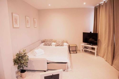 Un dormitorio blanco con una cama y un televisor. en Tetuan Boutique Apartment in Old Town Marbella, en Marbella