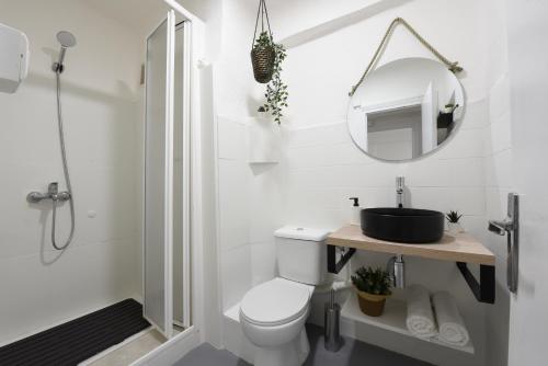 Baño blanco con aseo y espejo en Nordik Apartments Village - Arroyo "Rovaniemi" en Benalmádena