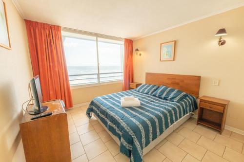 a bedroom with a bed with a view of the ocean at Oceana Suites Eurovista in Viña del Mar