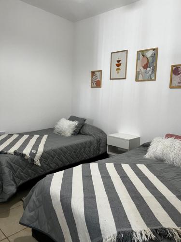 a bedroom with two beds and a white wall at Departamento Cristo del Portezuelo II in Chilecito