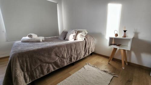 a bedroom with a bed with a night stand and a window at Departamento Los Fueguinos - Ushuaia in Ushuaia