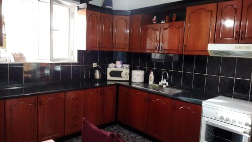 cocina con armarios de madera y microondas en LEVI Apartment, en Pogradec