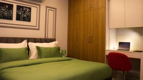 古爾岡的住宿－AVA Hotels and Corporate Suites，一间卧室配有绿色的床和红色椅子
