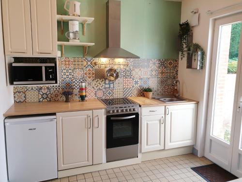 a kitchen with white cabinets and a stove top oven at Lam'Bray in Forges-les-Eaux