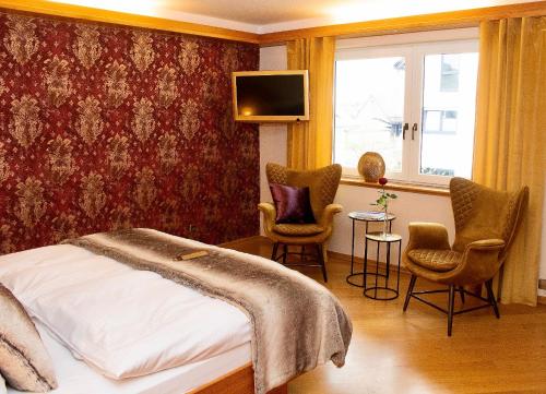 a bedroom with a bed and two chairs and a tv at Boutiquehotel Liebesglück - adults only in Winterberg