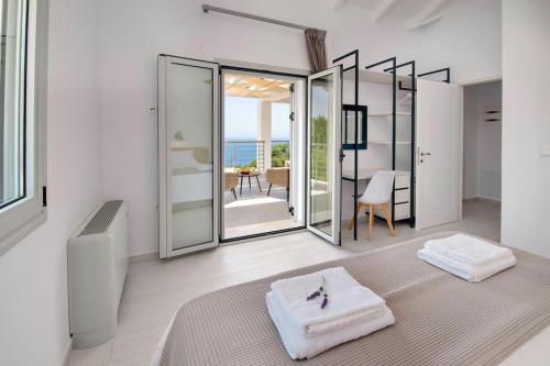 Tania Villa by PaxosRetreats في جايوس: غرفة بيضاء مع سرير وإطلالة على المحيط