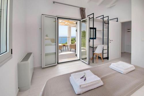 a white room with a bed and a view of the ocean at Tania Villas by PaxosRetreats in Gaios