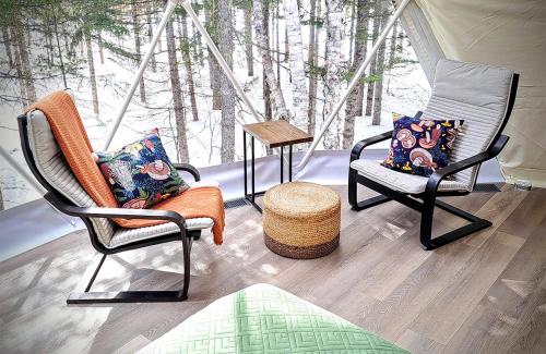 two chairs and a table in a room with trees at Quisibis Dômes in Riviere-Verte