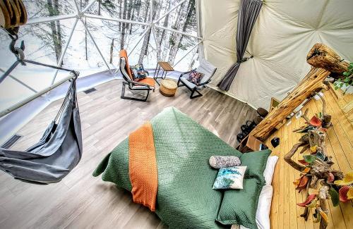 a room with a bed and a hammock in a tent at Quisibis Dômes in Riviere-Verte