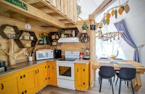 a kitchen with wooden cabinets and a table with chairs at Quisibis Dômes in Riviere-Verte
