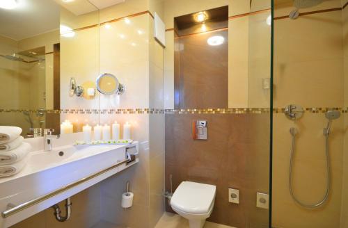 a bathroom with a shower and a toilet and a sink at Hotel Hanseatic - Adults Only in Kołobrzeg