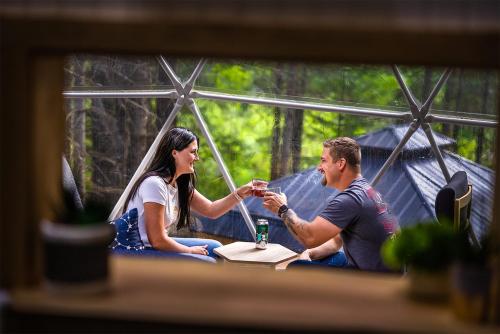 a man and woman sitting at a table in a tent at Quisibis Dômes in Riviere-Verte