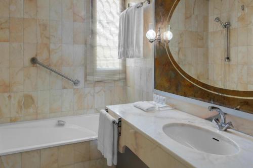 a bathroom with a sink and a mirror and a tub at Le Meridien Medina in Al Madinah