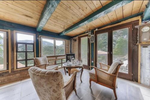ein Wohnzimmer mit einem Tisch, Stühlen und Fenstern in der Unterkunft White Scale Agroturizmo in Bar