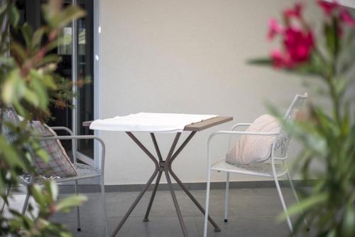 a white table and two chairs and flowers at Studio apartments Yucca, 2-min to the beach and 5 to Trogir in Trogir