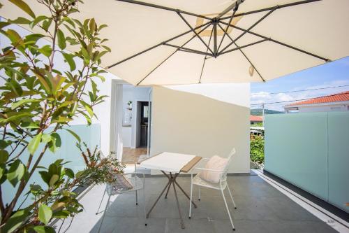 a patio with a table and chairs and an umbrella at Studio apartments Yucca, 2-min to the beach and 5 to Trogir in Trogir