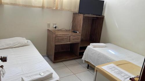 a hospital room with two beds and a tv at HOTEL BURITI in Cachoeira Alta