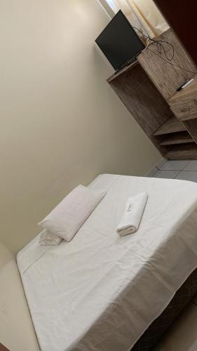 a white bed with two white pillows on it at HOTEL BURITI in Cachoeira Alta