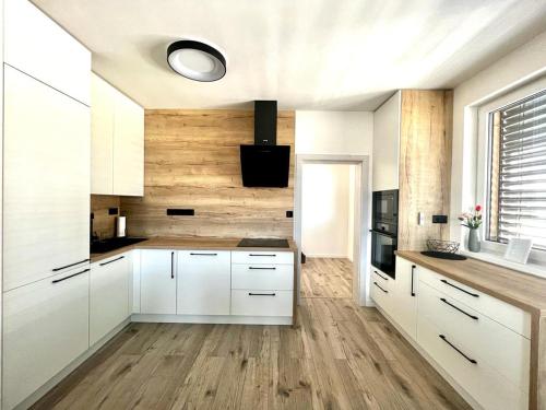 a kitchen with white cabinets and wooden floors at Urban ZION apartment in Liptovský Mikuláš