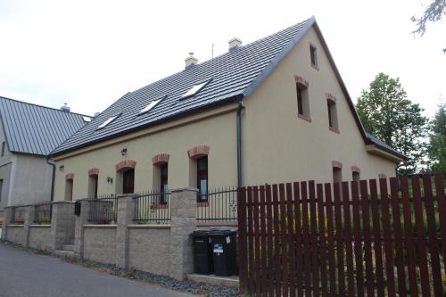 a white house with a black roof and a fence at Chalupa Madla in Kalek