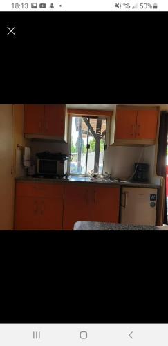 kuchnia z pomarańczowymi szafkami i oknem w obiekcie Mobile home dans camping frejus w Fréjus