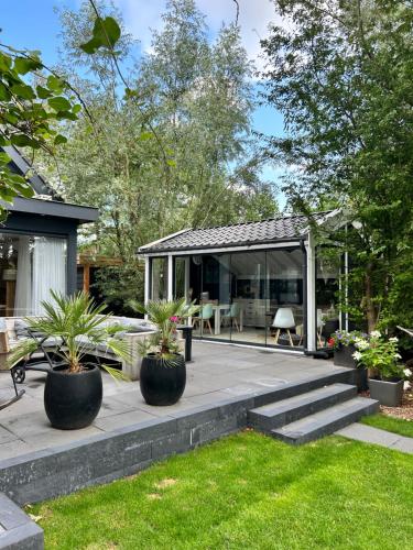 a patio with potted plants and a house at Casa aan de Plas, B&B met sauna en hottub of jacuzzi in Nieuwkoop