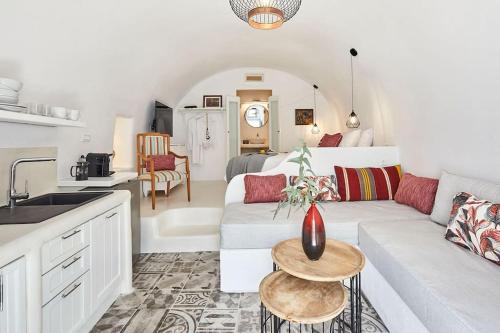 a living room with a white couch and a kitchen at Villa Agalitsa Cave Houses with Garden Courtyard in Megalochori