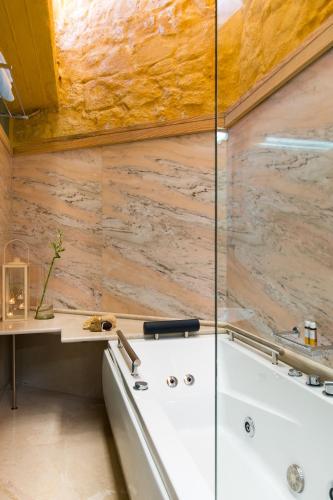 a bath tub in a bathroom with a stone wall at Eleni's Serenity - Discovering Sapphire Harmonies in Ravdhoúkha