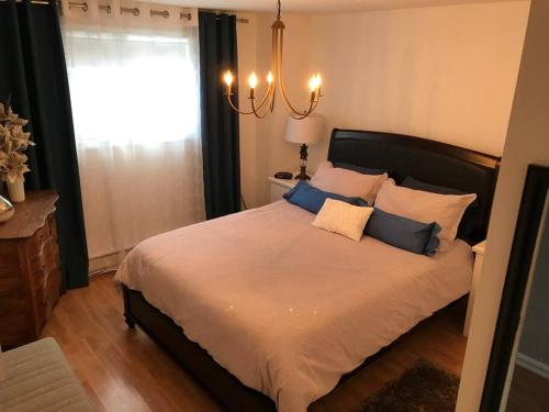 1 dormitorio con 1 cama grande con almohadas azules y blancas en Floral'Anse, en L'Anse-Saint-Jean