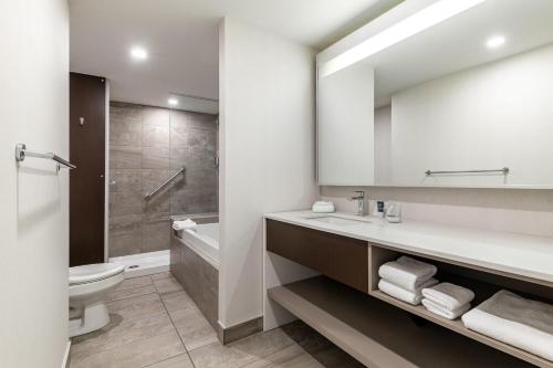 a bathroom with a sink and a toilet and a mirror at Four Points by Sheraton Lévis Convention Centre in Lévis