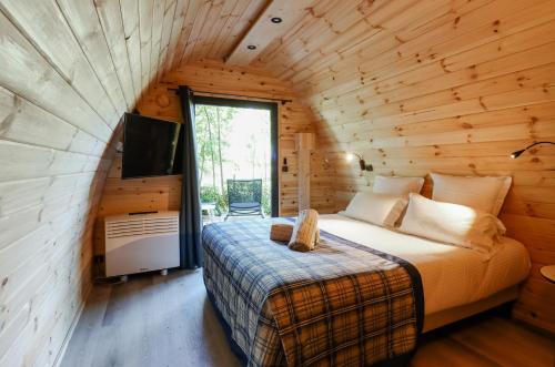 a bedroom in a log cabin with a bed and a tv at Les Jardins de Deauville in Saint-Martin-aux-Chartrains