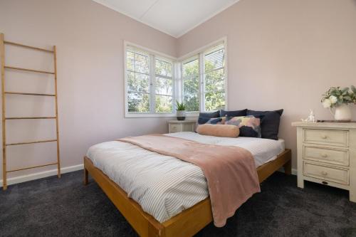 a bedroom with a bed and two windows at The Country Beach Oasis in Papamoa