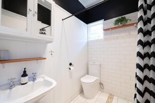a bathroom with a white toilet and a sink at The Country Beach Oasis in Papamoa