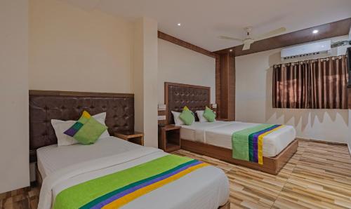 a bedroom with two beds with green and colorful pillows at Treebo Seven Olives in Mumbai
