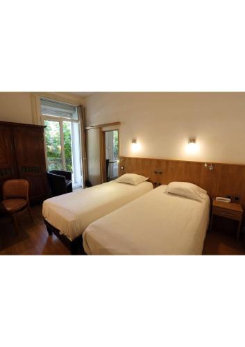 une chambre d'hôtel avec deux lits et une fenêtre dans l'établissement Hôtel Belleville, à Lamalou-les-Bains
